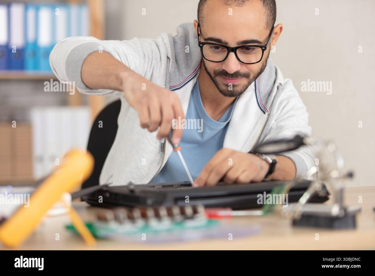 man repairing his laptop using a screwdriver Stock Photo