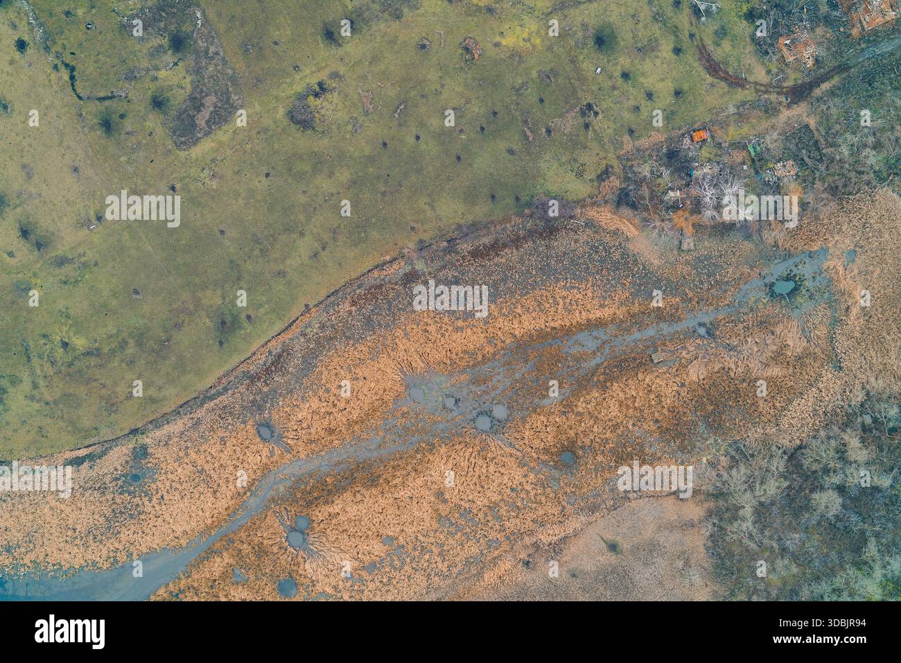 Aerial top-down view of a vulnerable wetland area, where vivid orange ...