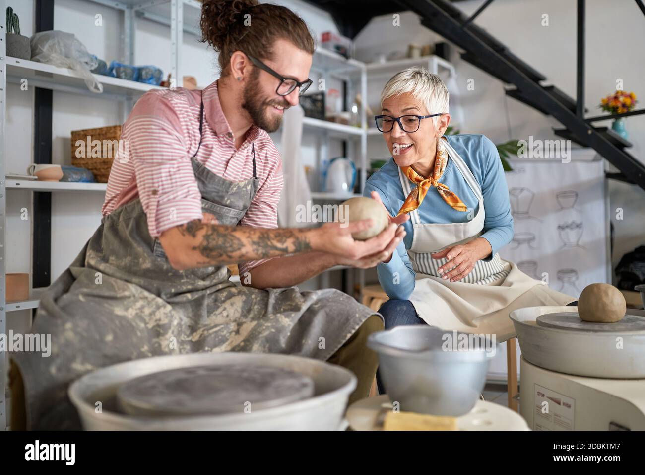 pottery workshop. Happy beginner Making pot from clay while teacher explaining how. Creative, hobby ,activities concept Stock Photo