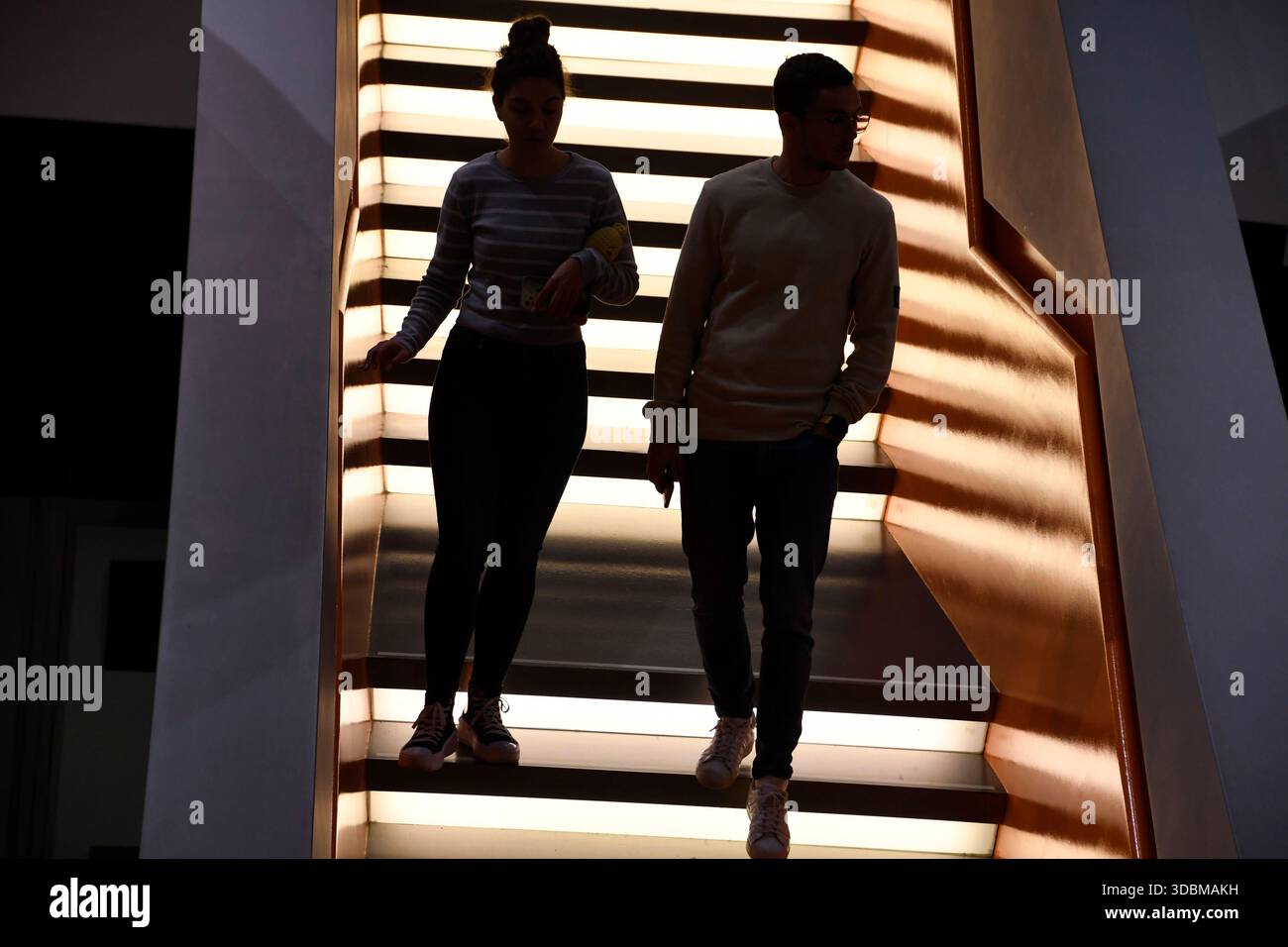 Two people walking on illuminated stairs with black steps hi-res stock ...