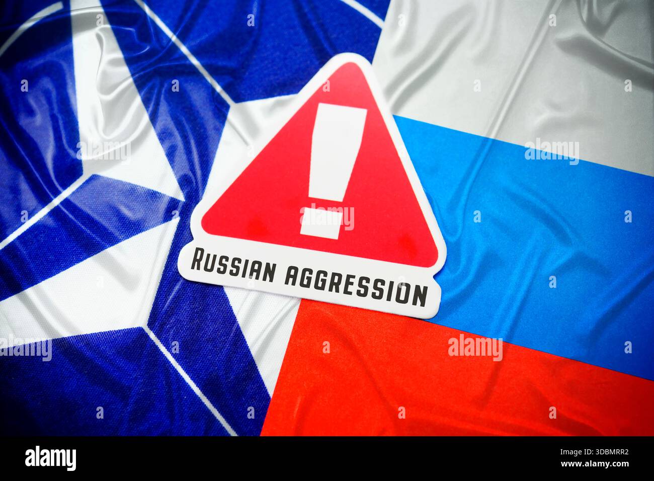 The flags of NATO and Russia with danger sign and inscription Russian Aggression, photomontage Stock Photo