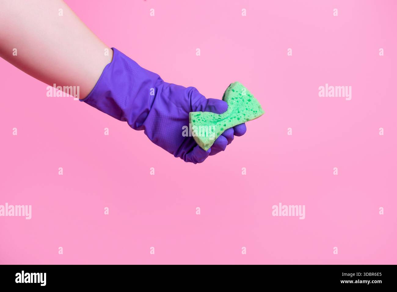 Above is a photo of a cellulose sponge and purple gloves isolated on a pink background Stock Photo