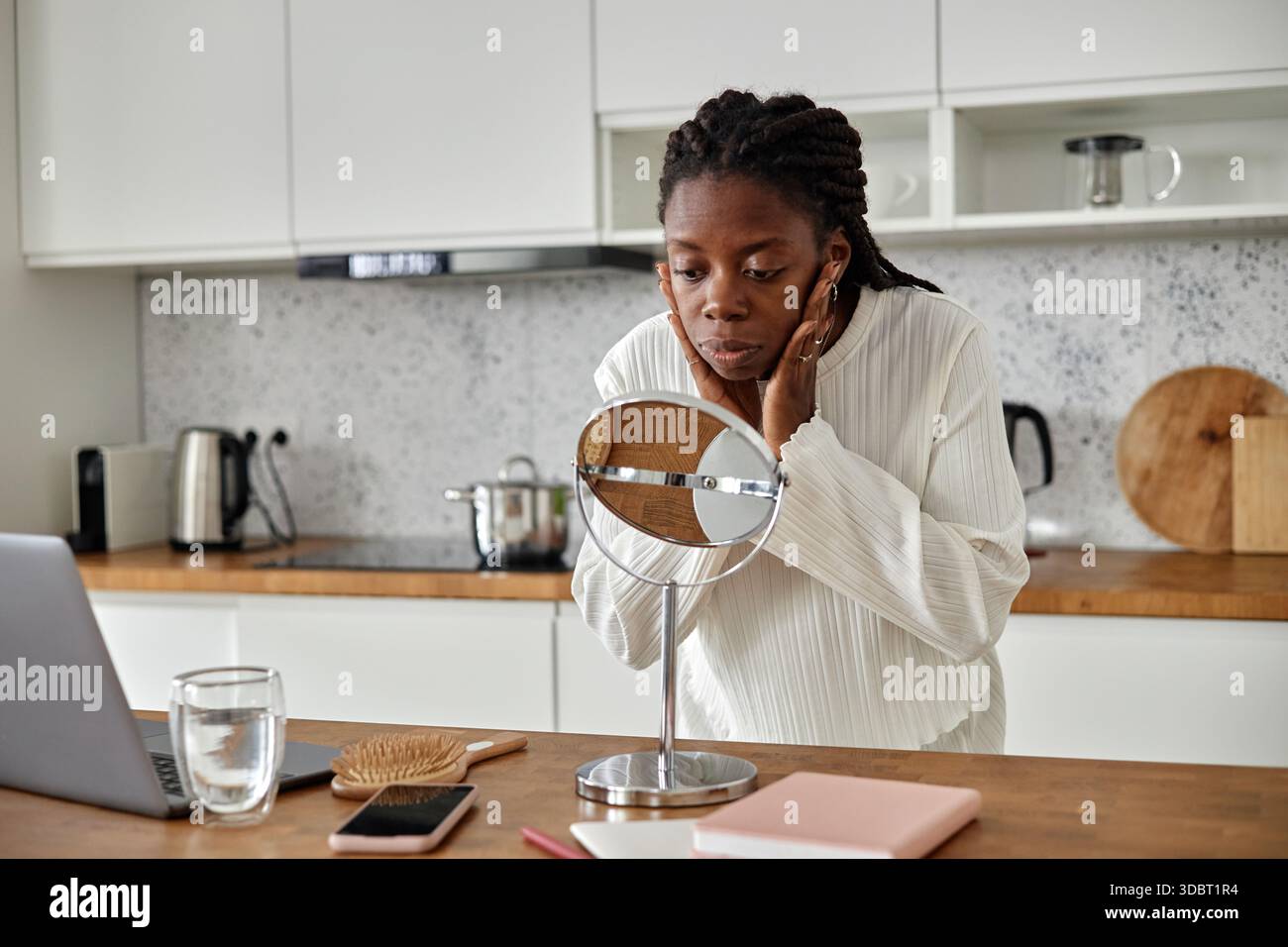 Young Black Woman Examining Face in Mirror during Morning Skincare Routine Stock Photo