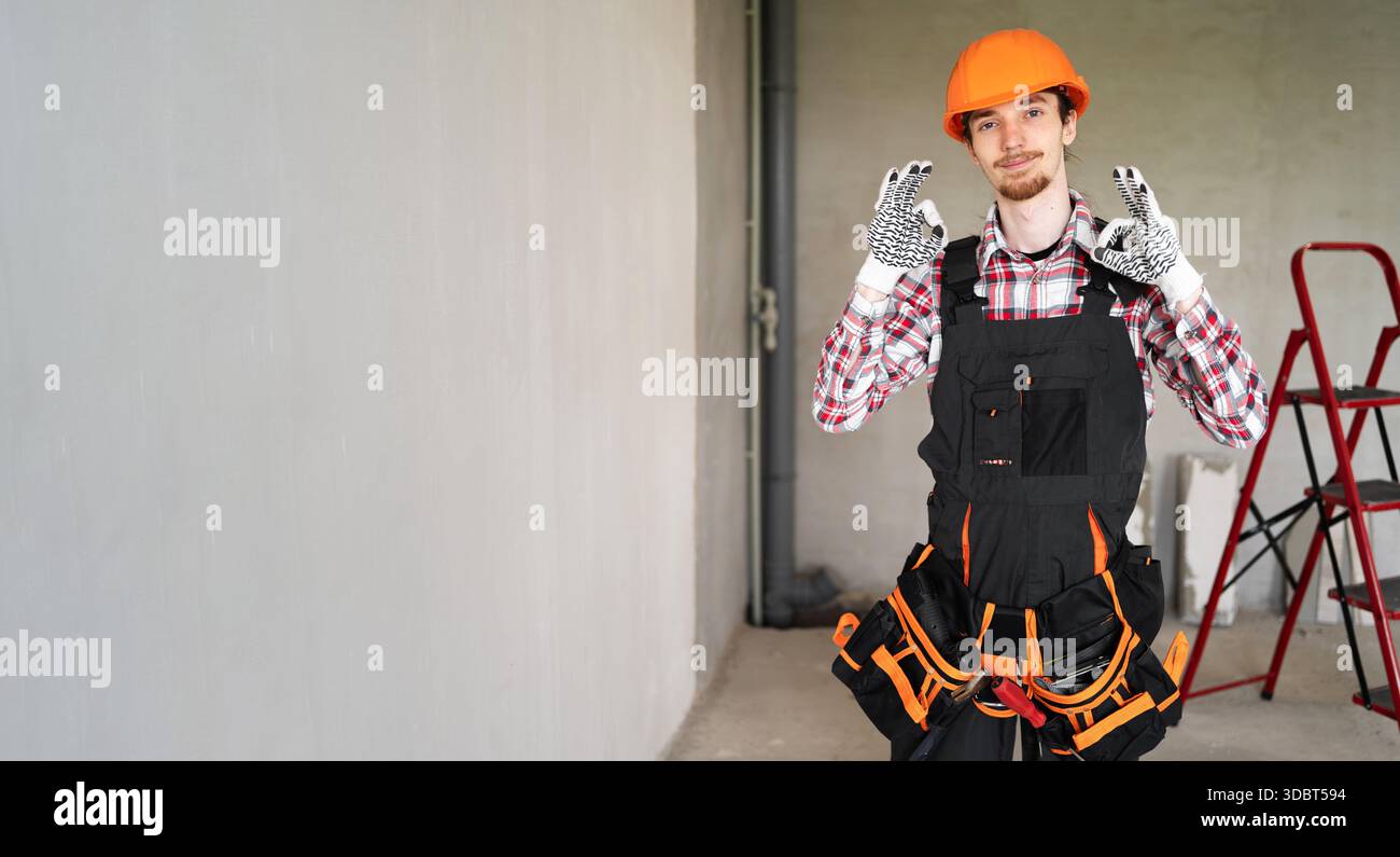 male laborer, builder or repairman wearing helmet and tool belt ready for repairing or building says not bad guarantee excellent result showing ok ges Stock Photo