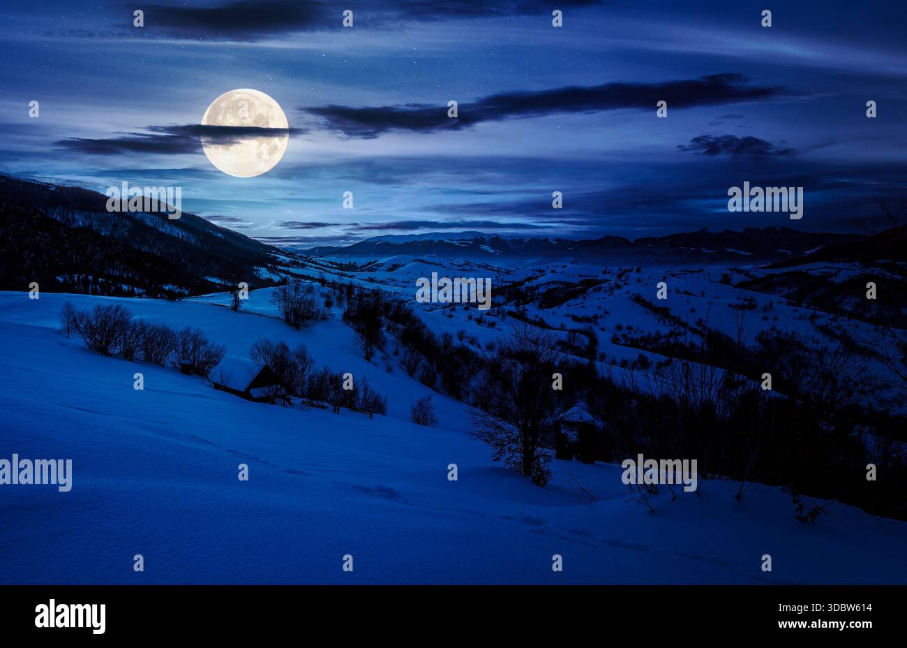 winter in mountainous countryside at night. gorgeous cloudy sky over the snow covered hills in full moon light. wide mountain ridge in a far distance. Stock Photo