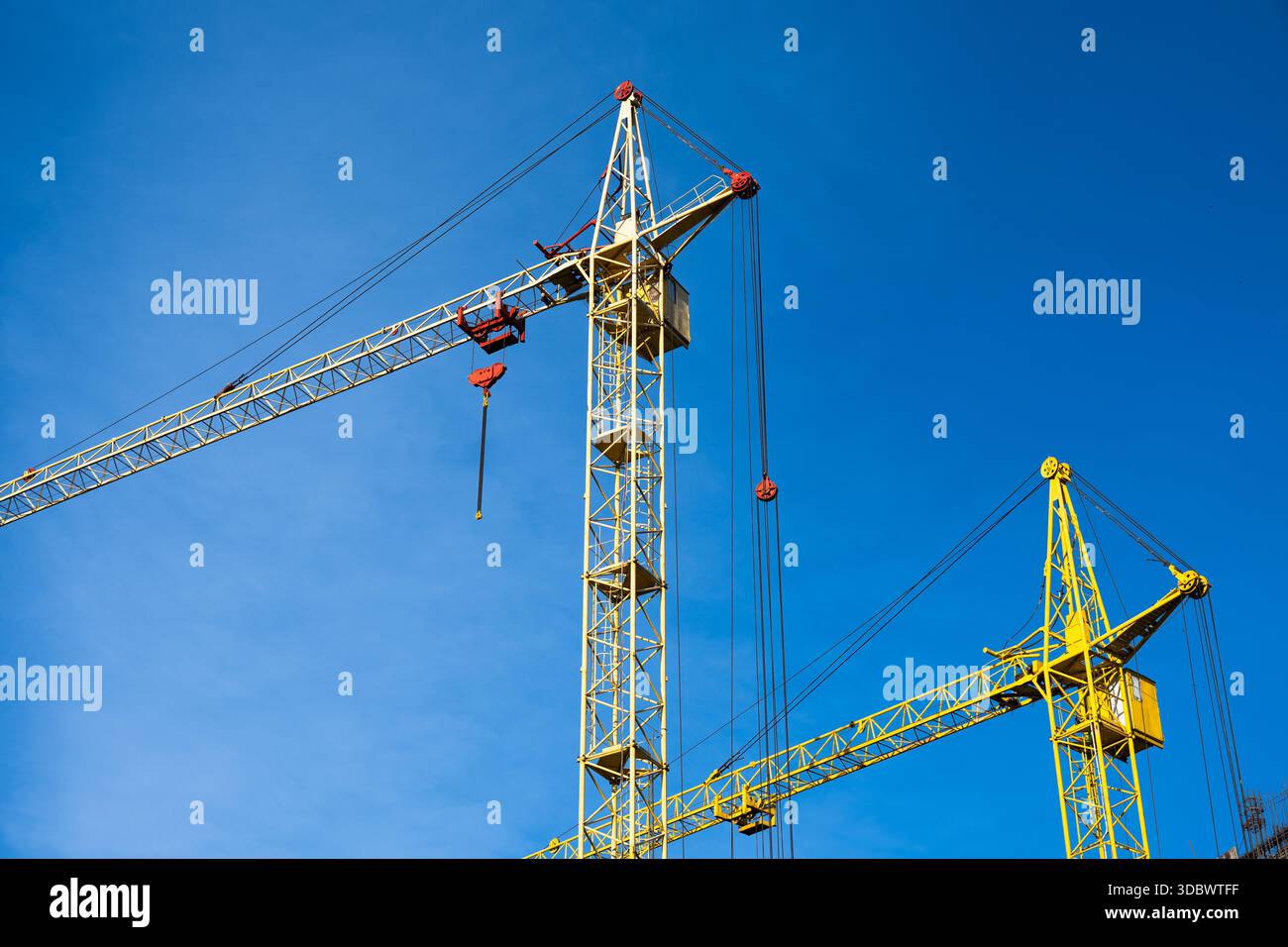 Two yellow construction cranes against  blue sky . Stock Photo