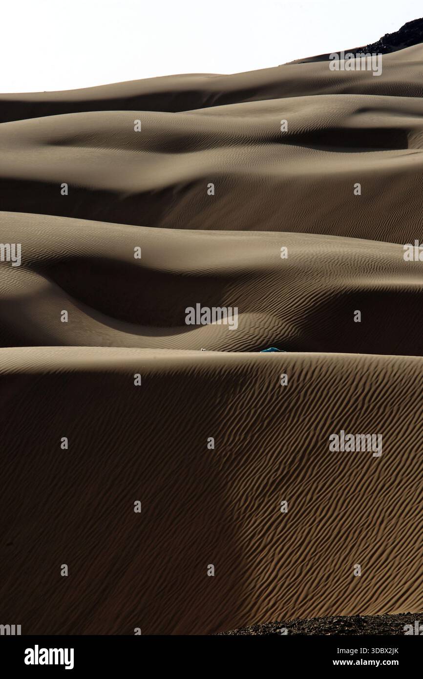 View of rippling waves of sand dunes, sculpted by wind, create a mesmerizing pattern of light and shadow across the desert landscape, Noshki, Balochis Stock Photo