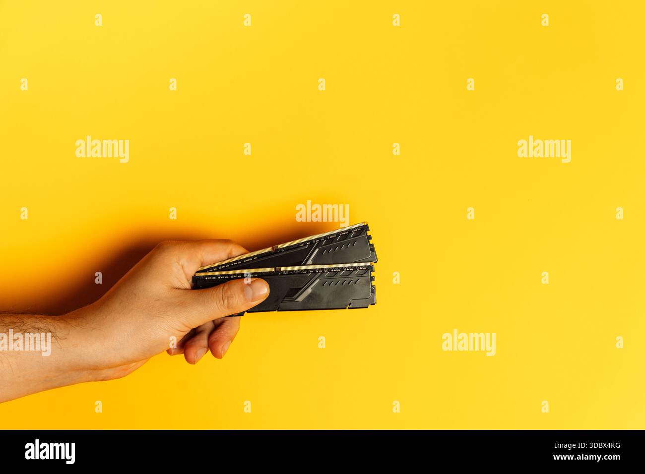 Hand presenting stack of desktop RAM modules on yellow background Stock Photo