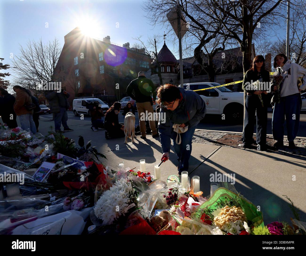 A woman lights a candle at a memorial set up in front of the Barus and ...
