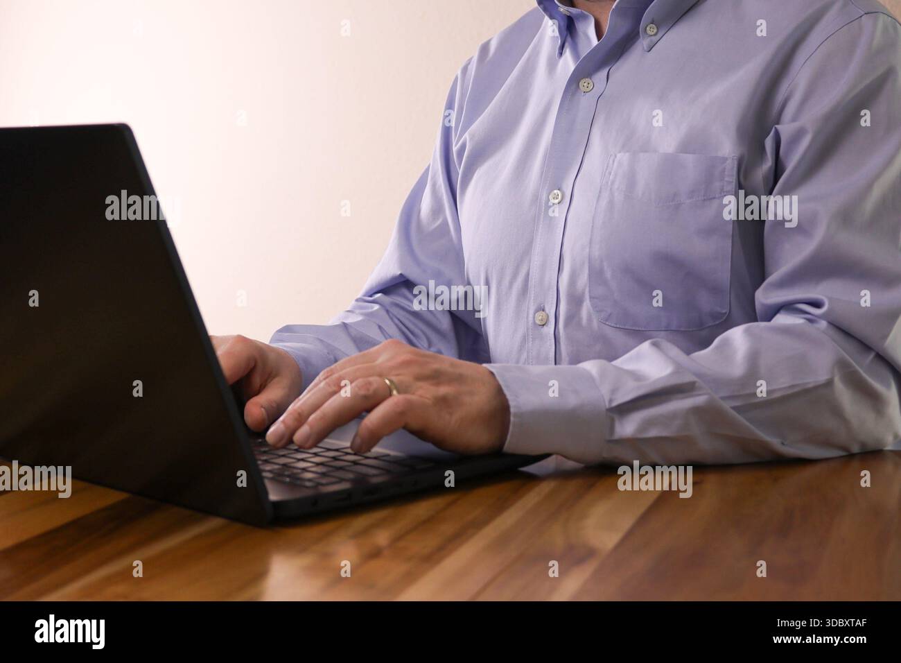 Anonymous Man Typing on Laptop at Wooden Table Stock Photo