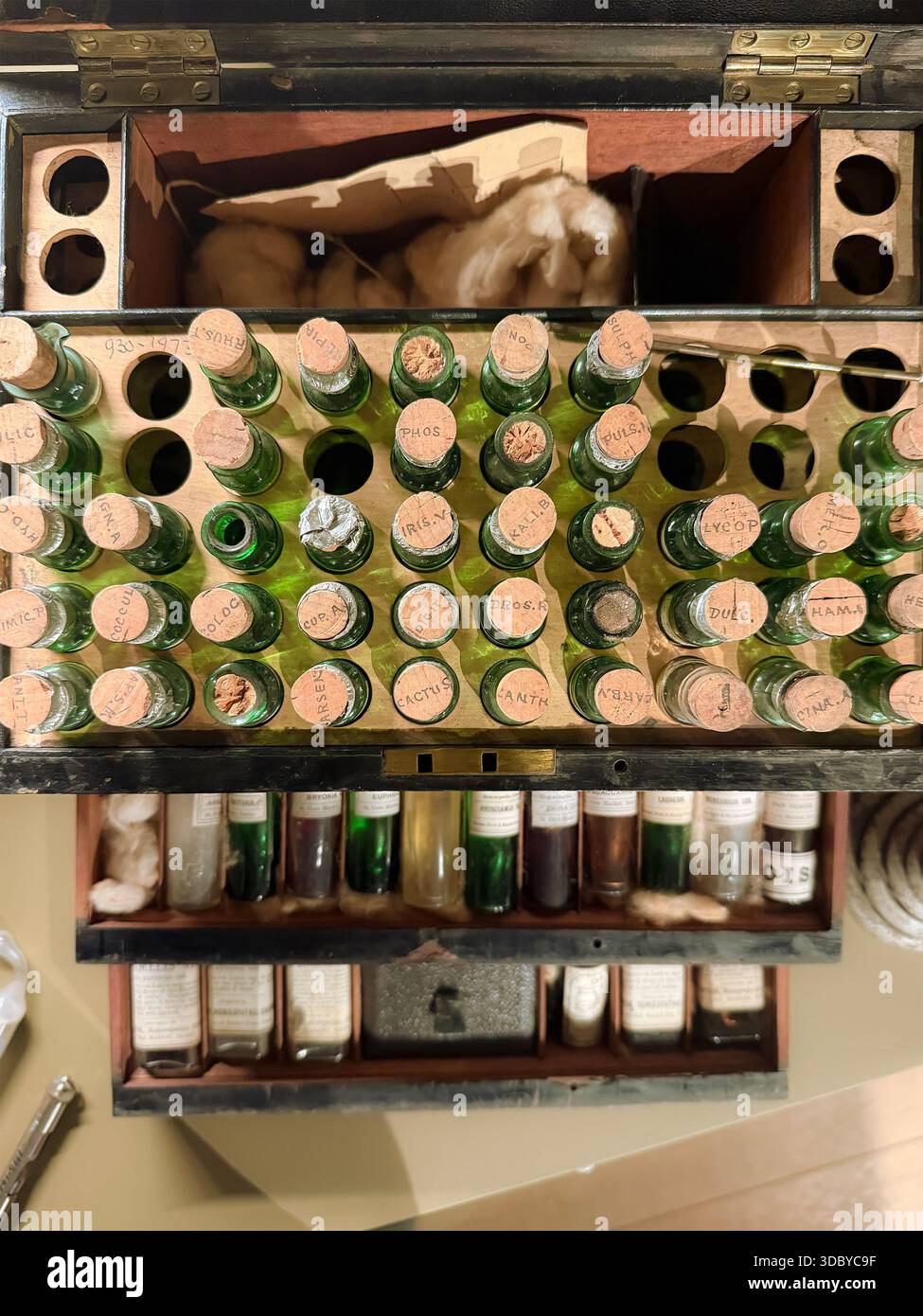 Overhead view of a vintage apothecary or medical kit with glass bottles, cork stoppers, and compartments containing cotton and labeled vials - Smartphone Captured Stock Image