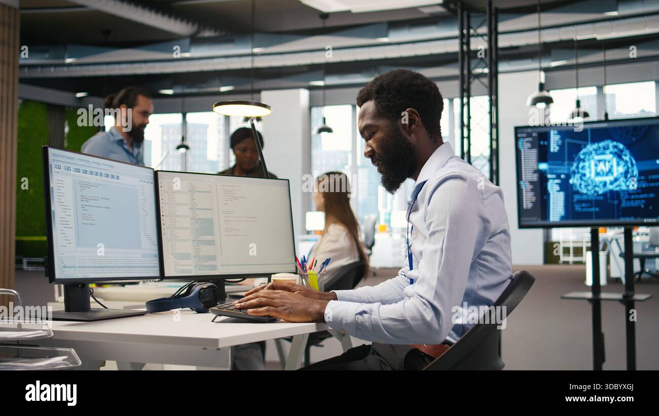System administrator in tech startup office using PC, troubleshooting hardware and software issues. IT professional at work monitoring and optimizing performance using computer, camera A Stock Photo