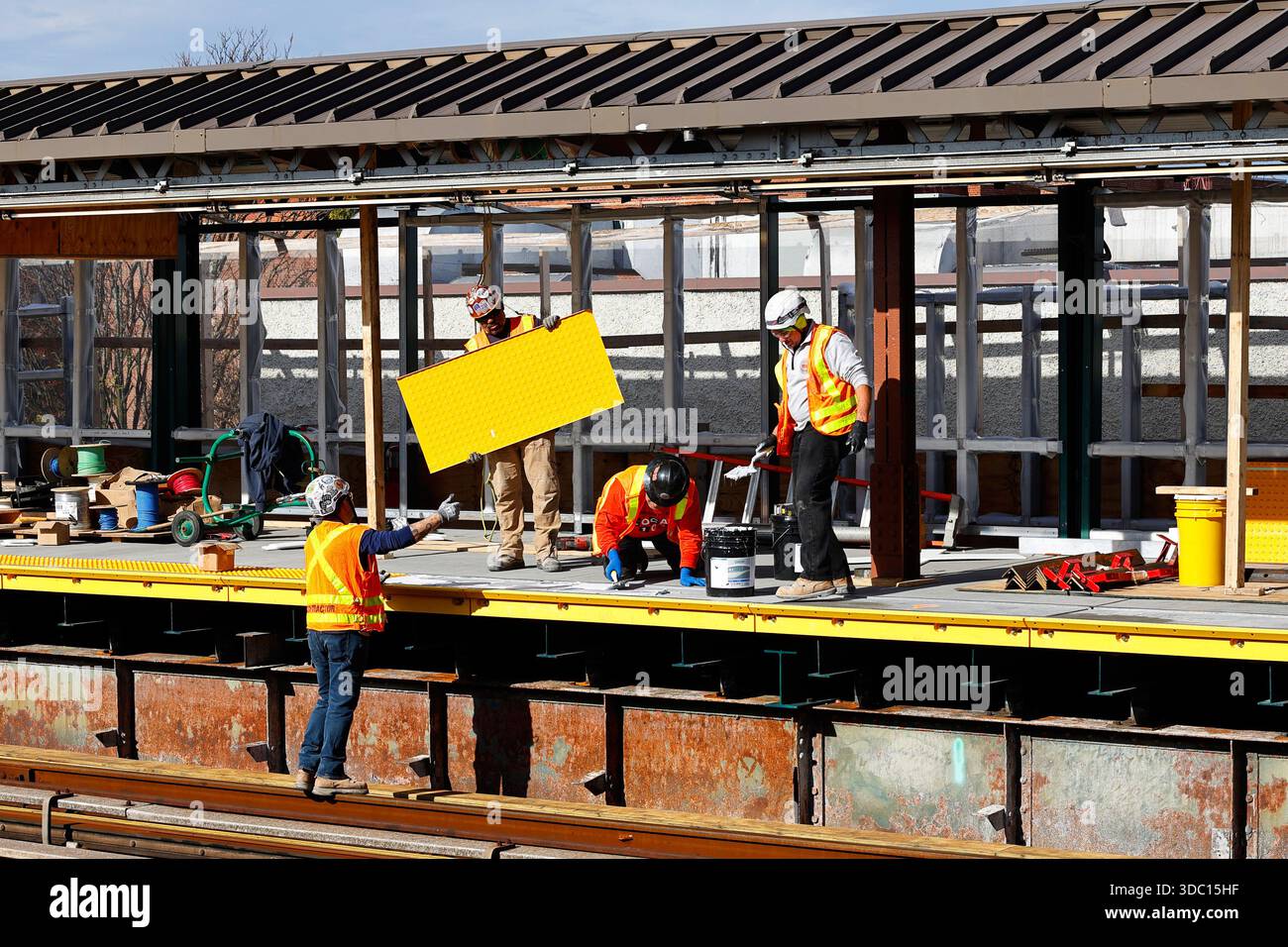 Construction workers install tactile paving, aka detectible warning surface, aka truncated domes at a subway train platform in New York City. Stock Photo