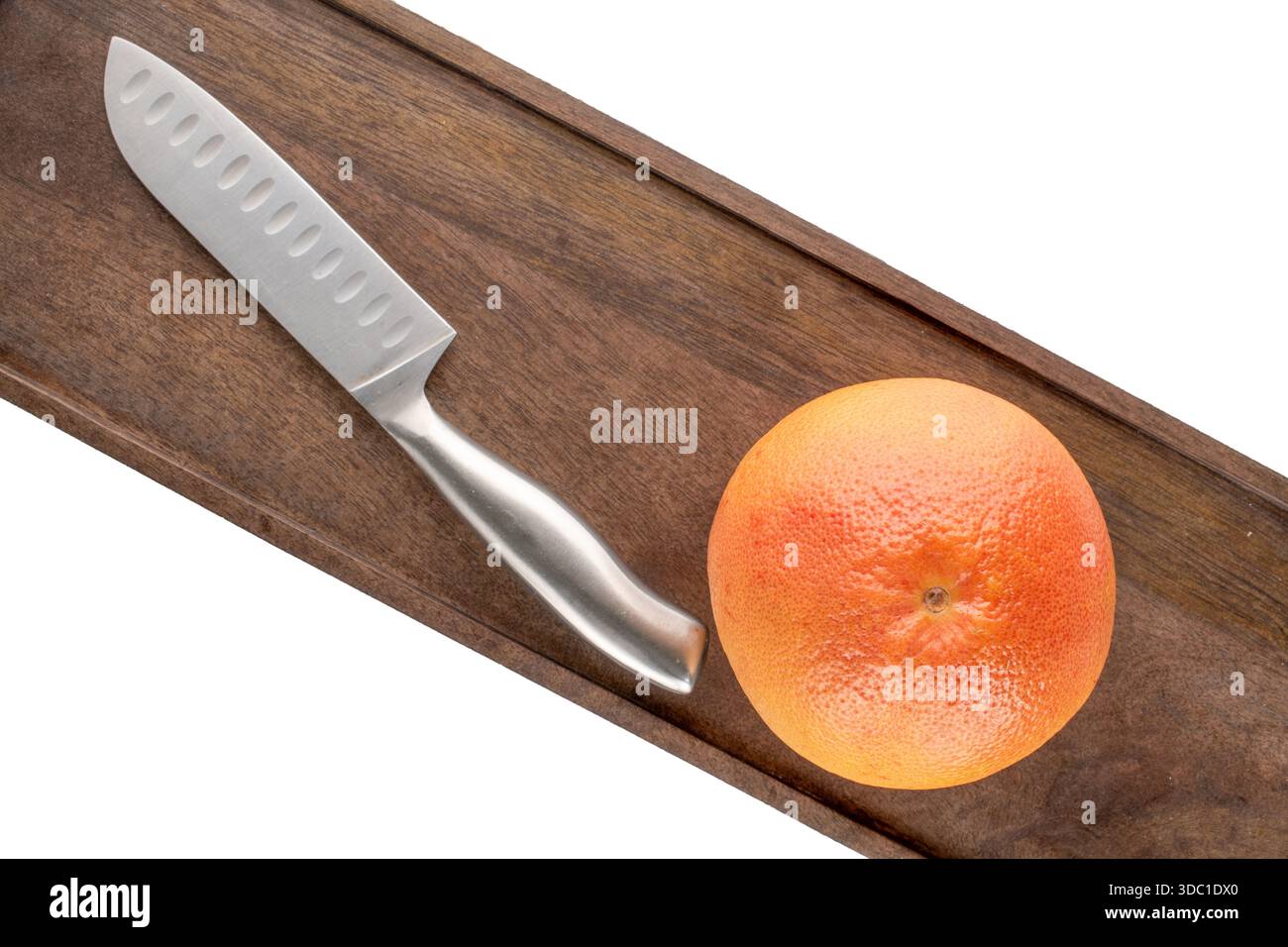One juicy grapefruit with wooden kitchen board and knife on white background, close-up, top view. Stock Photo