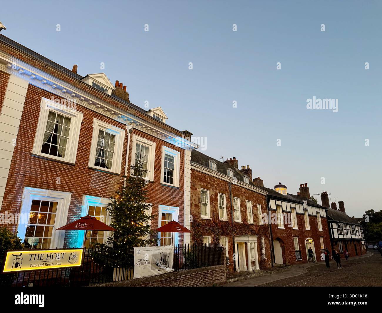 Cathedral Close in Exeter at dusk, with historic townhouses, festive lighting and a Christmas tree outside The Holt. - Smartphone Captured Stock Image
