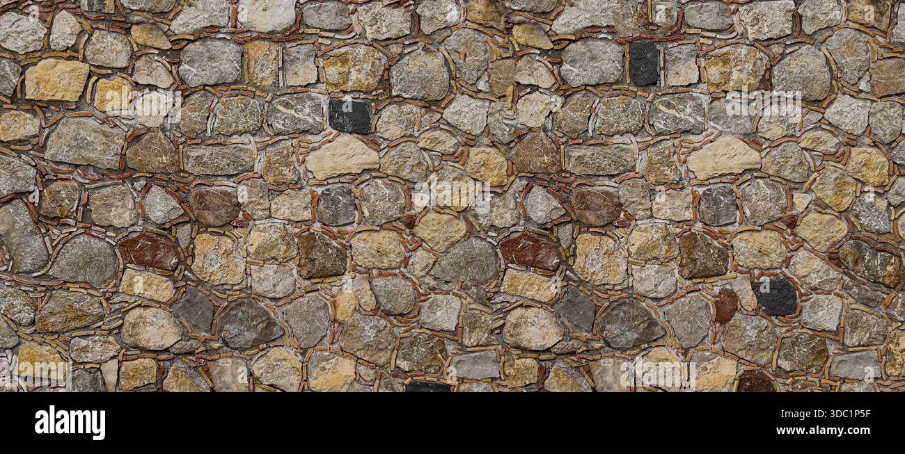 Irregular natural stone wall creating a rustic textured background Stock Photo