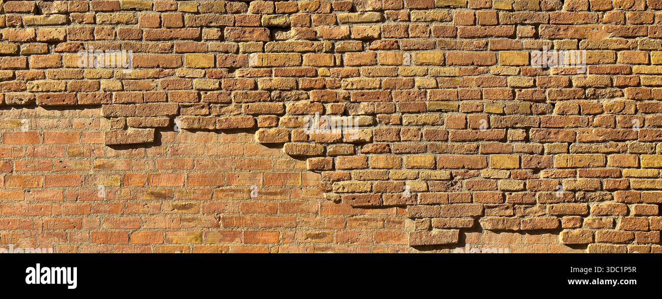 Old weathered brick wall texture with crumbling bricks creating a rustic background Stock Photo