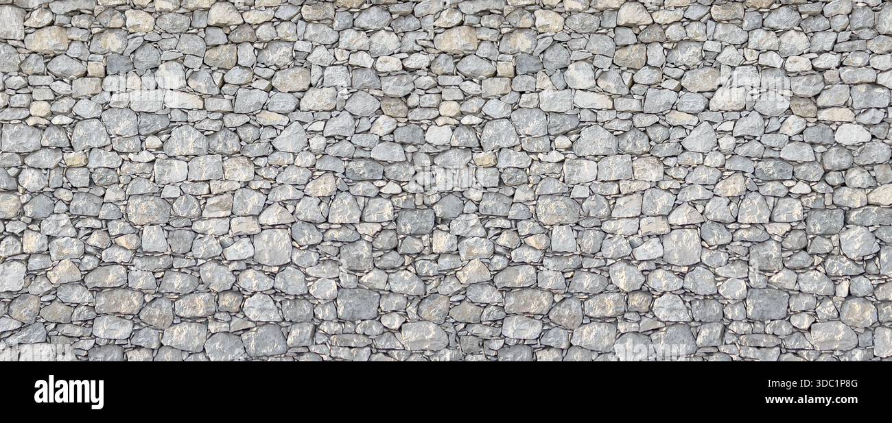 Gray stone wall showing a rough surface texture and solid masonry pattern Stock Photo