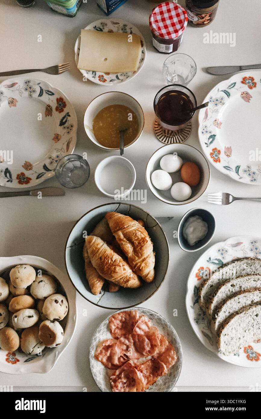 Breakfast table with croissants, eggs, bread, cheese, and jam Stock Photo
