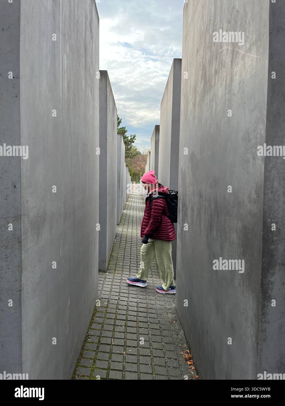 A girl in contrasting coloured clothes walking through the Holocaust Memorial in Berlin - Smartphone Captured Stock Image