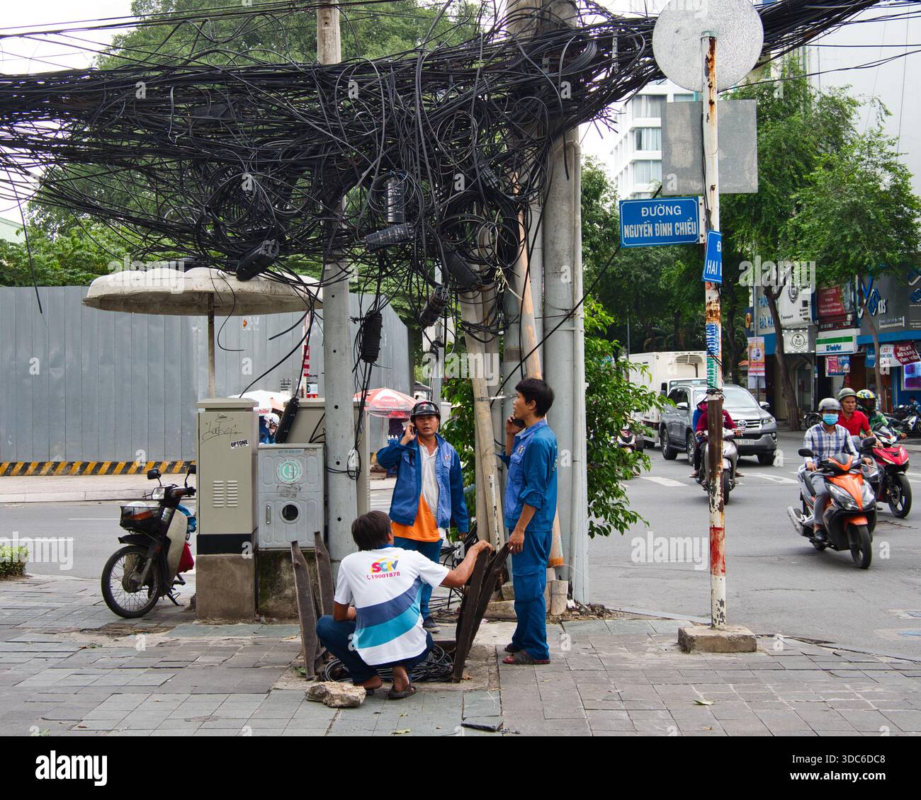 HO CHI MINH-Vietnam-August 17, 2019,Ho Chi Minh City, Vietnam - Utility workers near an extreme tangle of overhead electrical and communication cables Stock Photo
