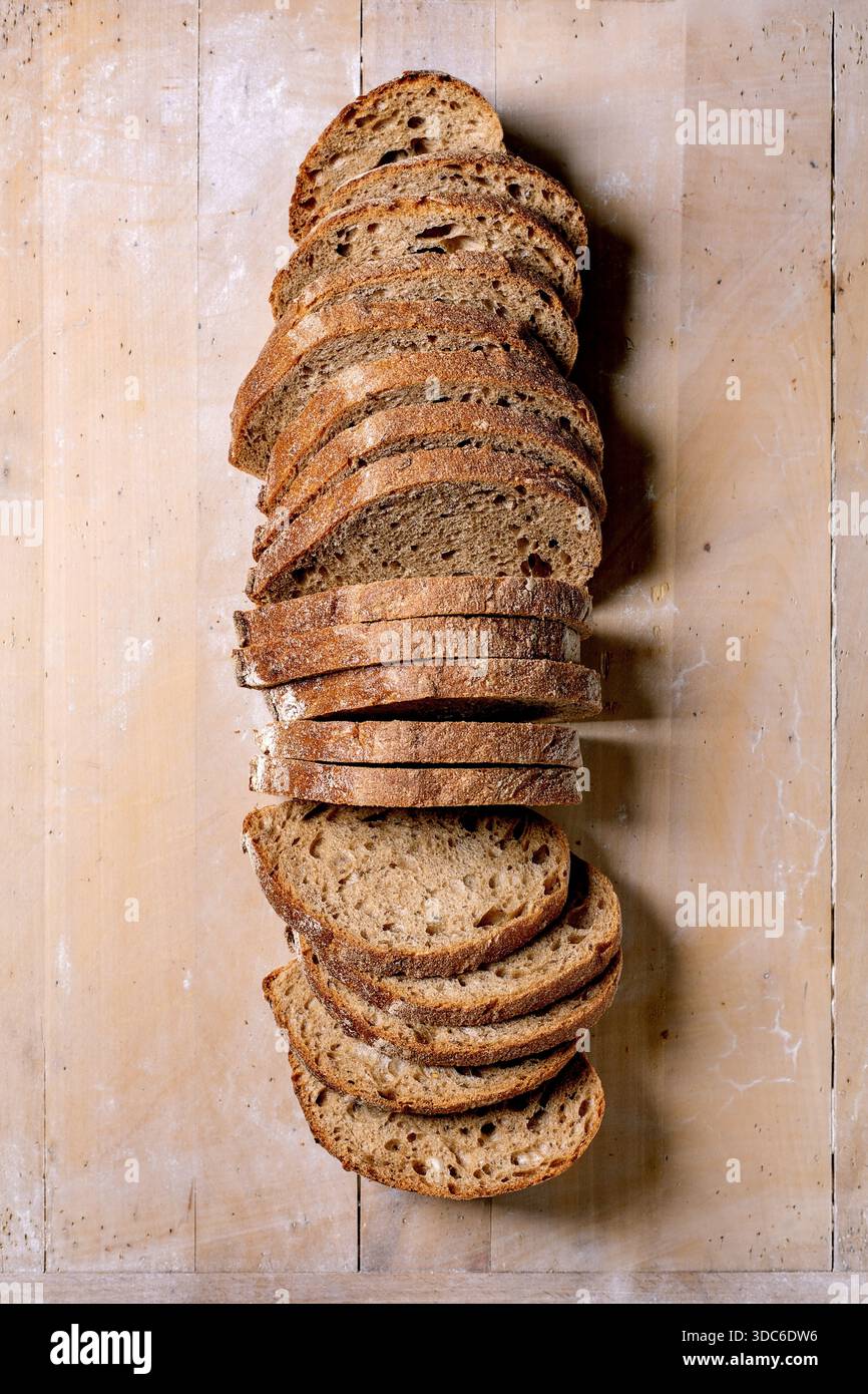 Fresh sliced sourdough bread loaf arranged on wooden background. Rustic homemade bread with crunchy crust and soft interior texture. Stock Photo