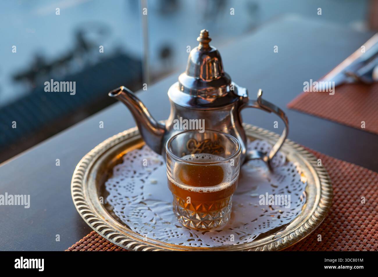 A warm glass of traditional Moroccan mint tea served on a brass 
