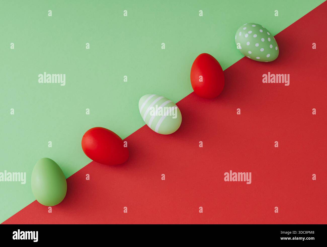 Spring composition with colored Easter eggs on green and red background. Creative Easter concept. Festive holiday layout. Flat lay. Stock Photo