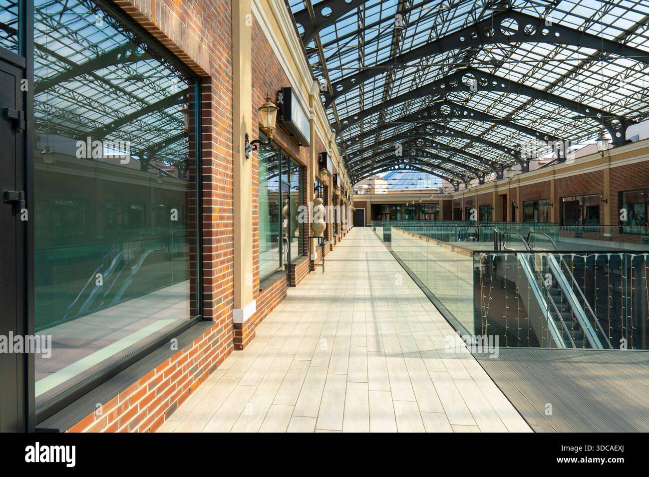 Interior of a modern shopping center with large glass roof, brick walls, and empty walkways. Beautiful architecture of a retail building Stock Photo
