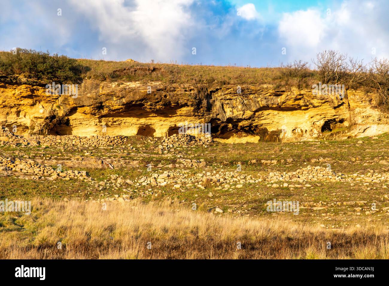 Layered rock formations with small caves and dry stone walls scattered ...