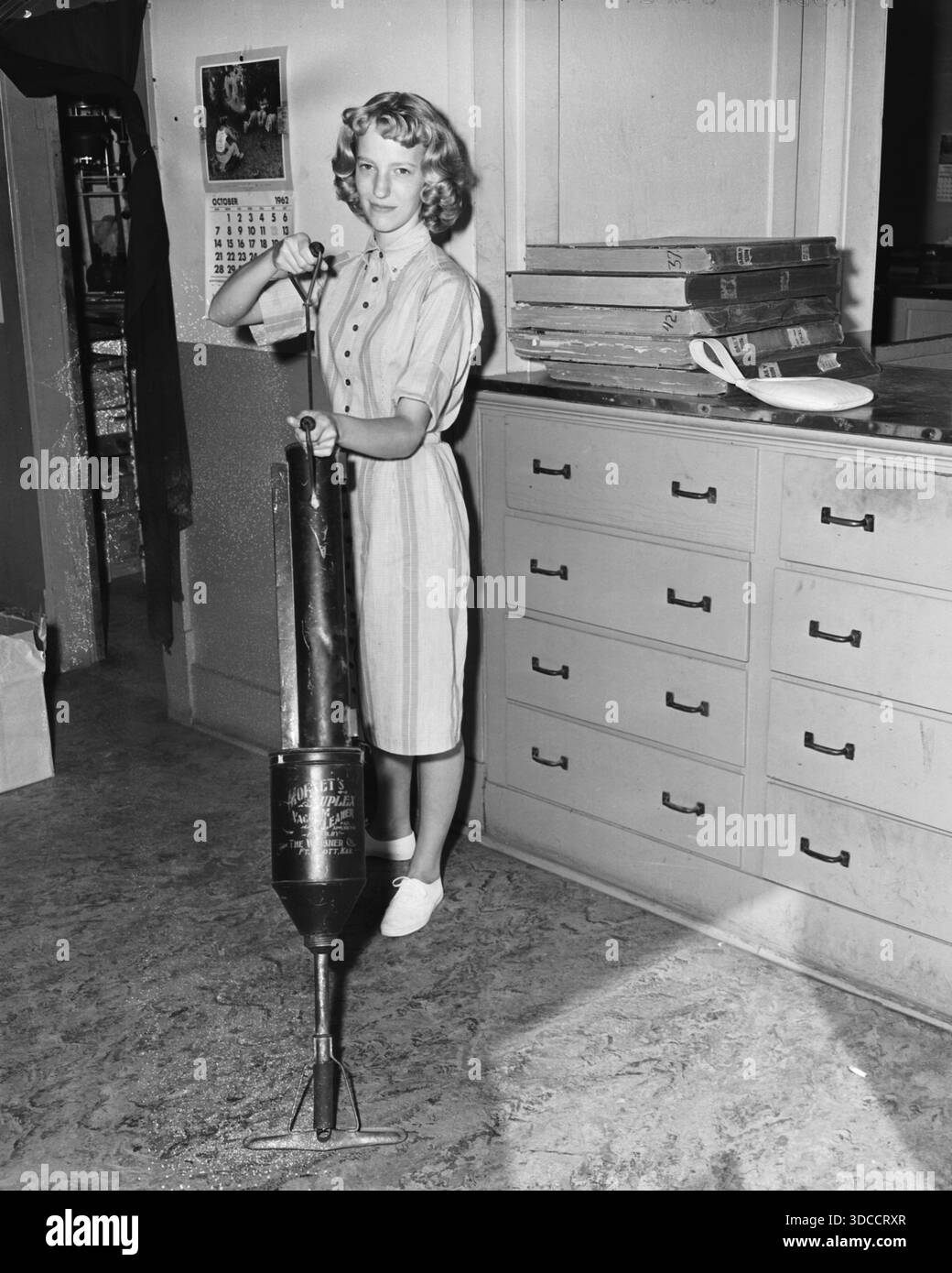 A woman displays an old fashioned manual vacuum cleaner floor sweeper ...