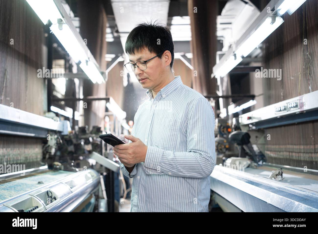 asian man using smart phone in textile factory Stock Photo