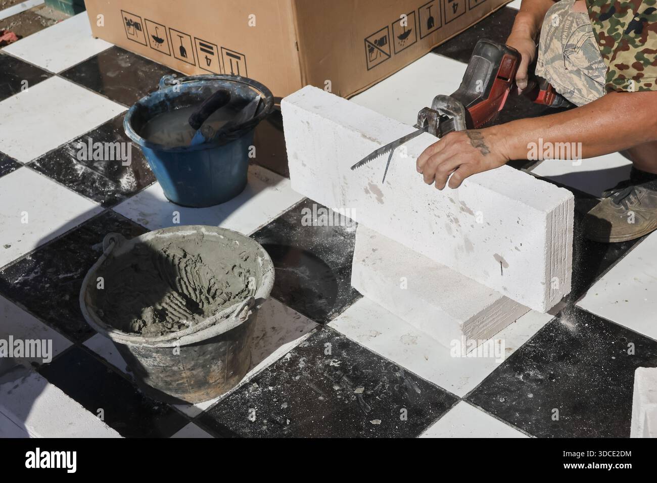 Construction worker carefully cutting white aerated concrete block with ...