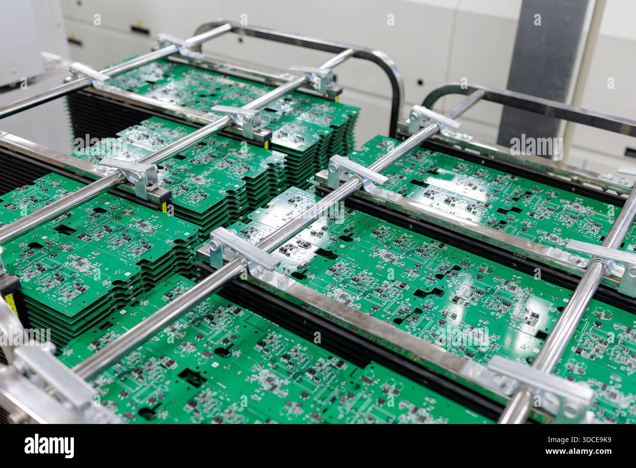 Stacks of green printed circuit boards clamped in metal racks inside ...