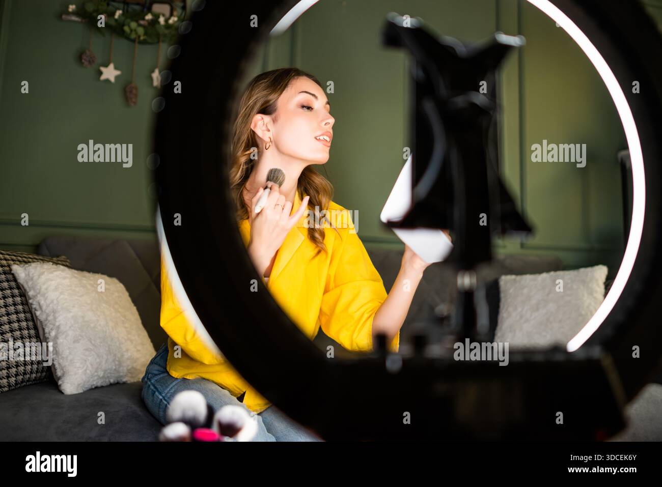 Influencer recording a beauty routine at home. She is using ring light ...