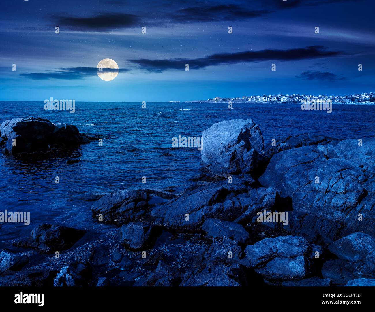 rocky shore of the sea coast under blue sky at night. beautiful view of coastal scene in full moon light. resort scenery during vacation season in sum Stock Photo