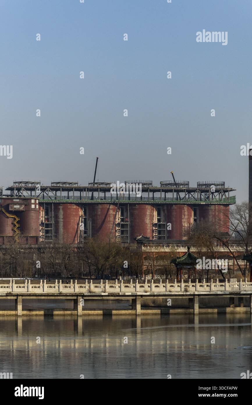 View of industrial silos rise majestically beyond the serene waters and the ornate bridge architecture in Beijing, Beijing, China. Stock Photo