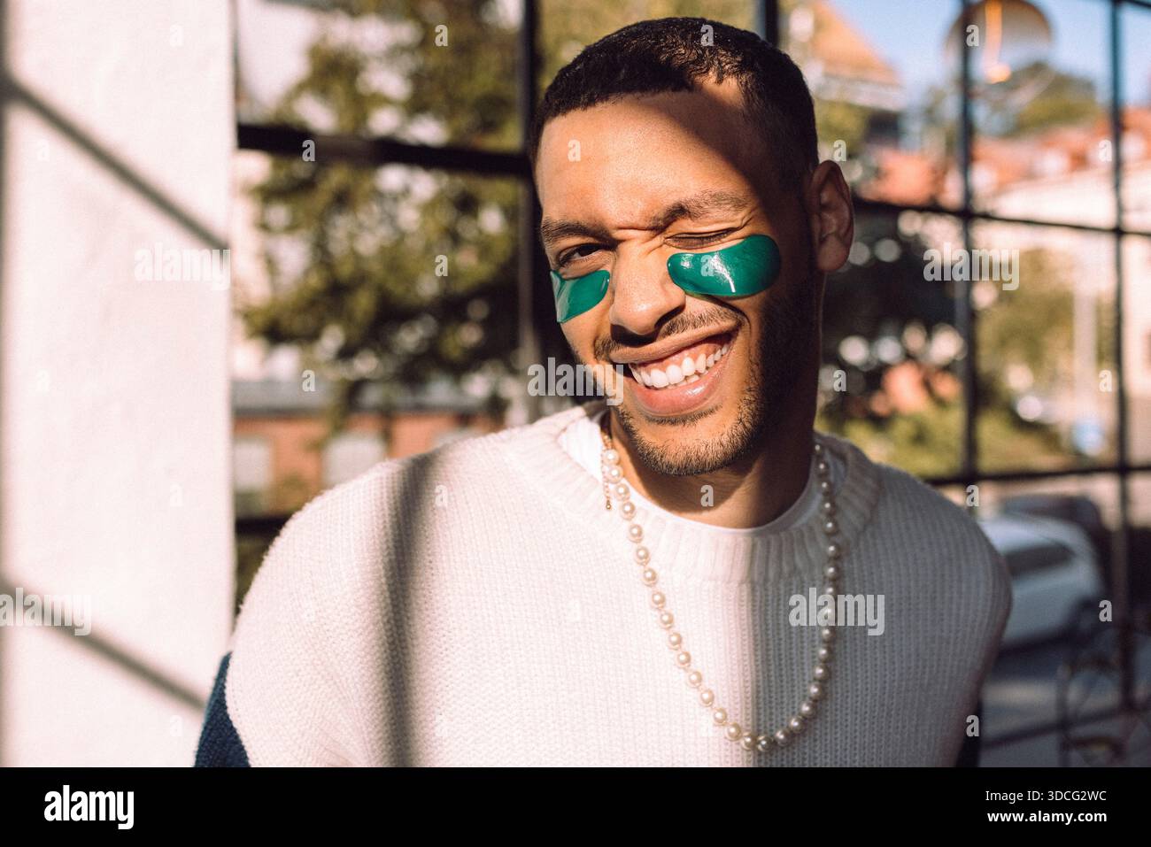 Sunlight shining on smiling man with under-eye patch winking at camera Stock Photo