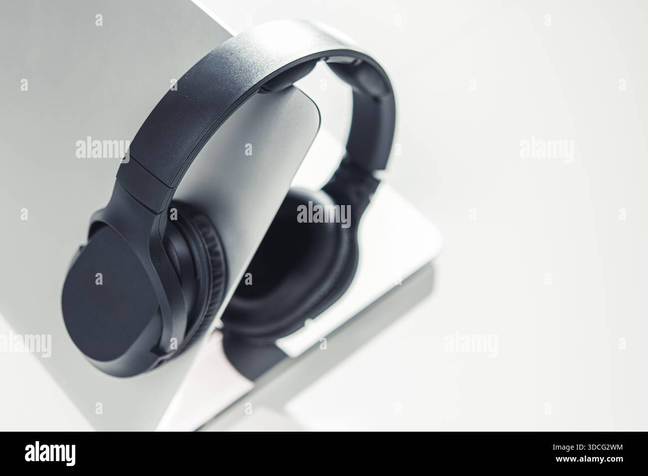 Headphones are placed on a laptop in a well-lit office area during daytime hours. Stock Photo