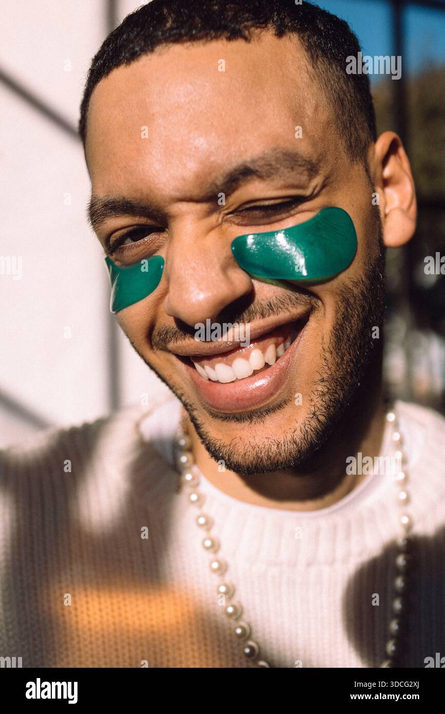 Portrait of smiling man with under-eye patch winking at camera Stock Photo