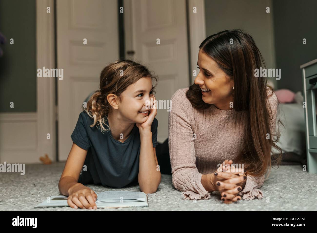 Smiling woman lying on carpet with daughter in home Stock Photo