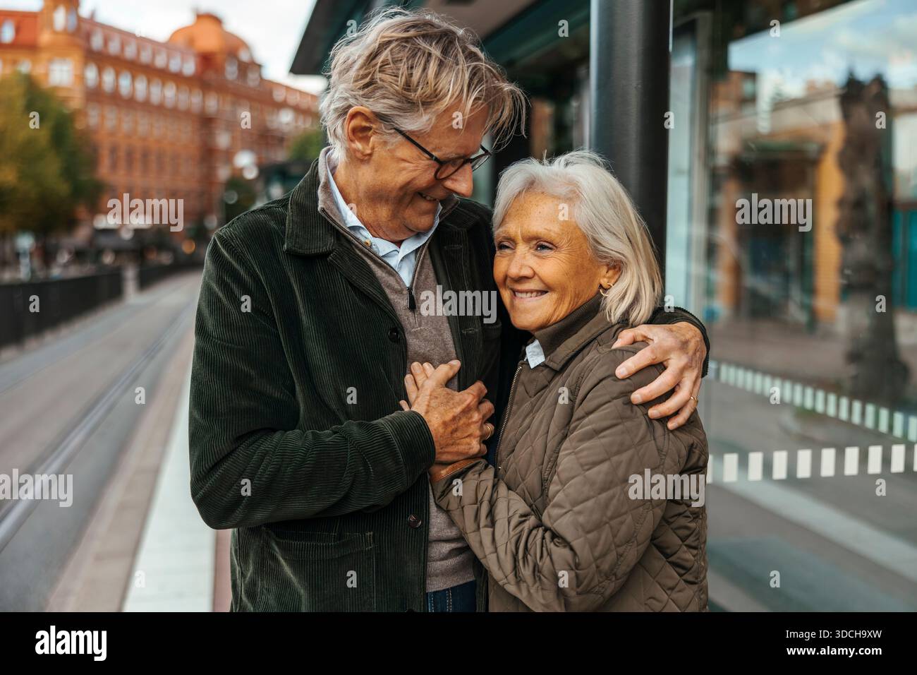 Affectionate senior man embracing woman while waiting at bus stop Stock Photo