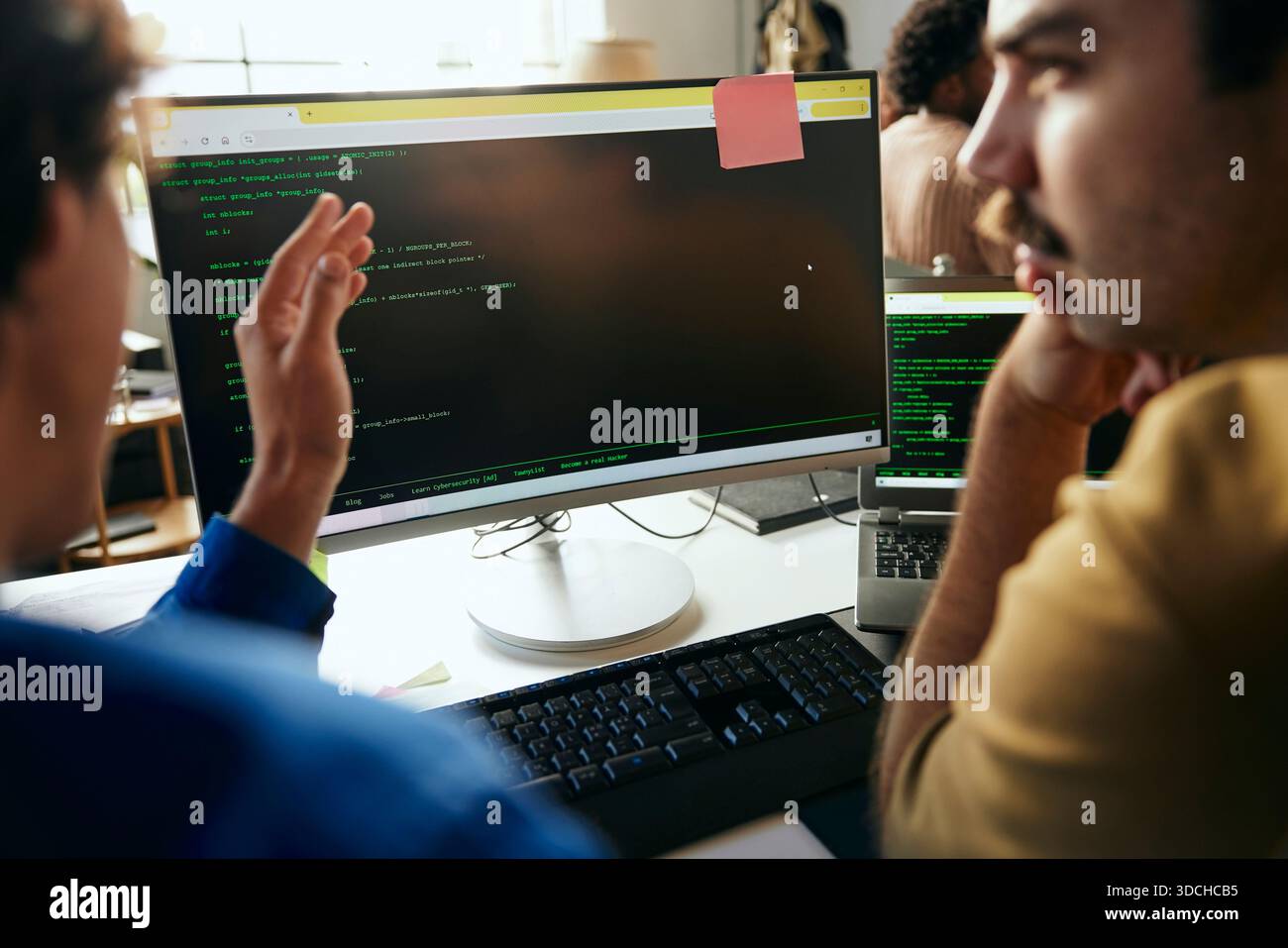 Male programmers discussing ideas with each other while coding on desktop PC in office Stock Photo