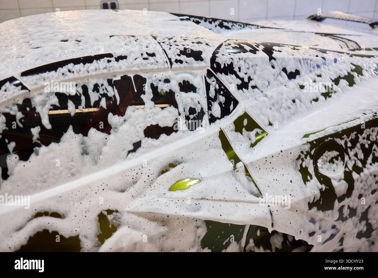 A luxury car is undergoing a foam wash treatment to enhance its ...