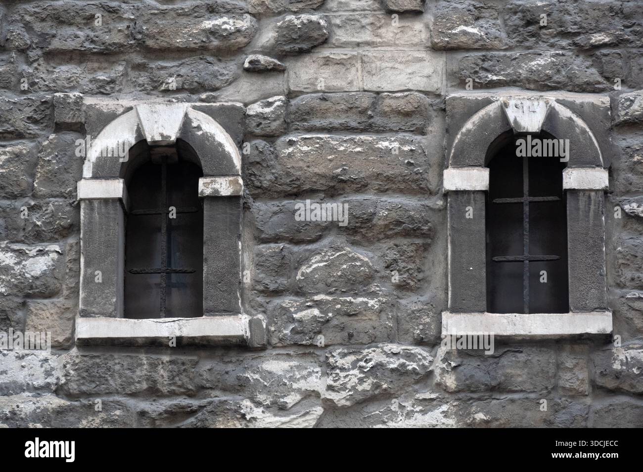 Small arched windows in grey stone church wall for use as a background texture Stock Photo