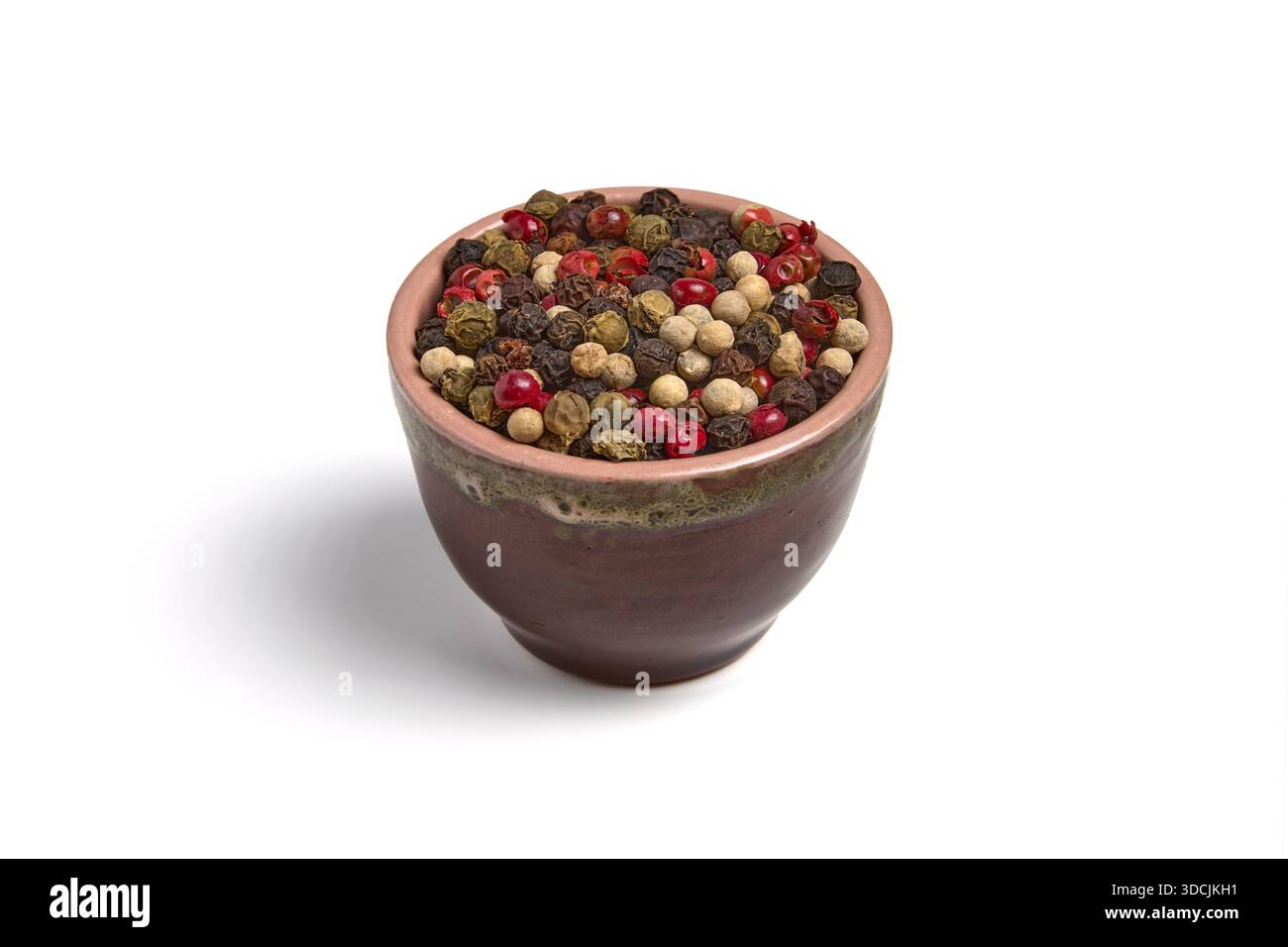 Mix of multi-colored peppercorns in a ceramic bowl isolated on white background. Stock Photo