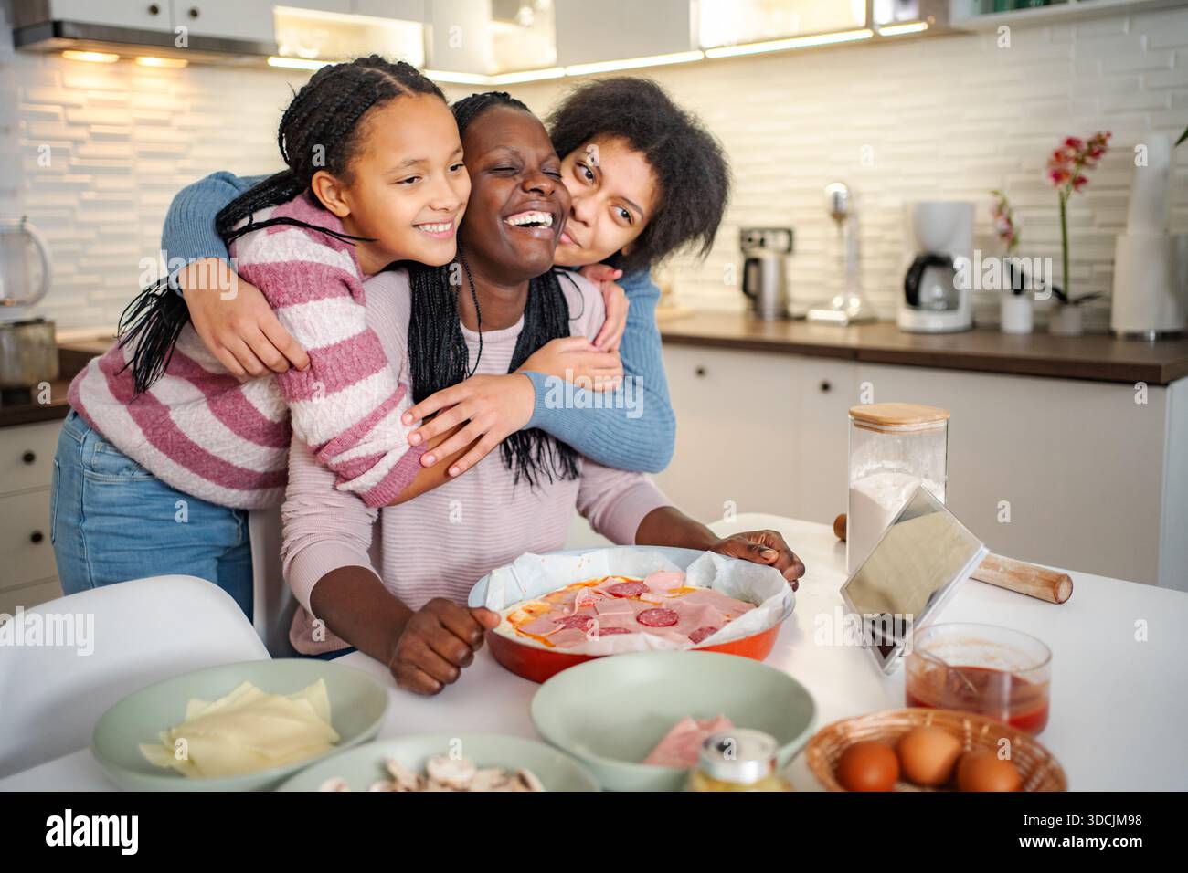 Black mother and daughters enjoying cooking pizza together Stock Photo