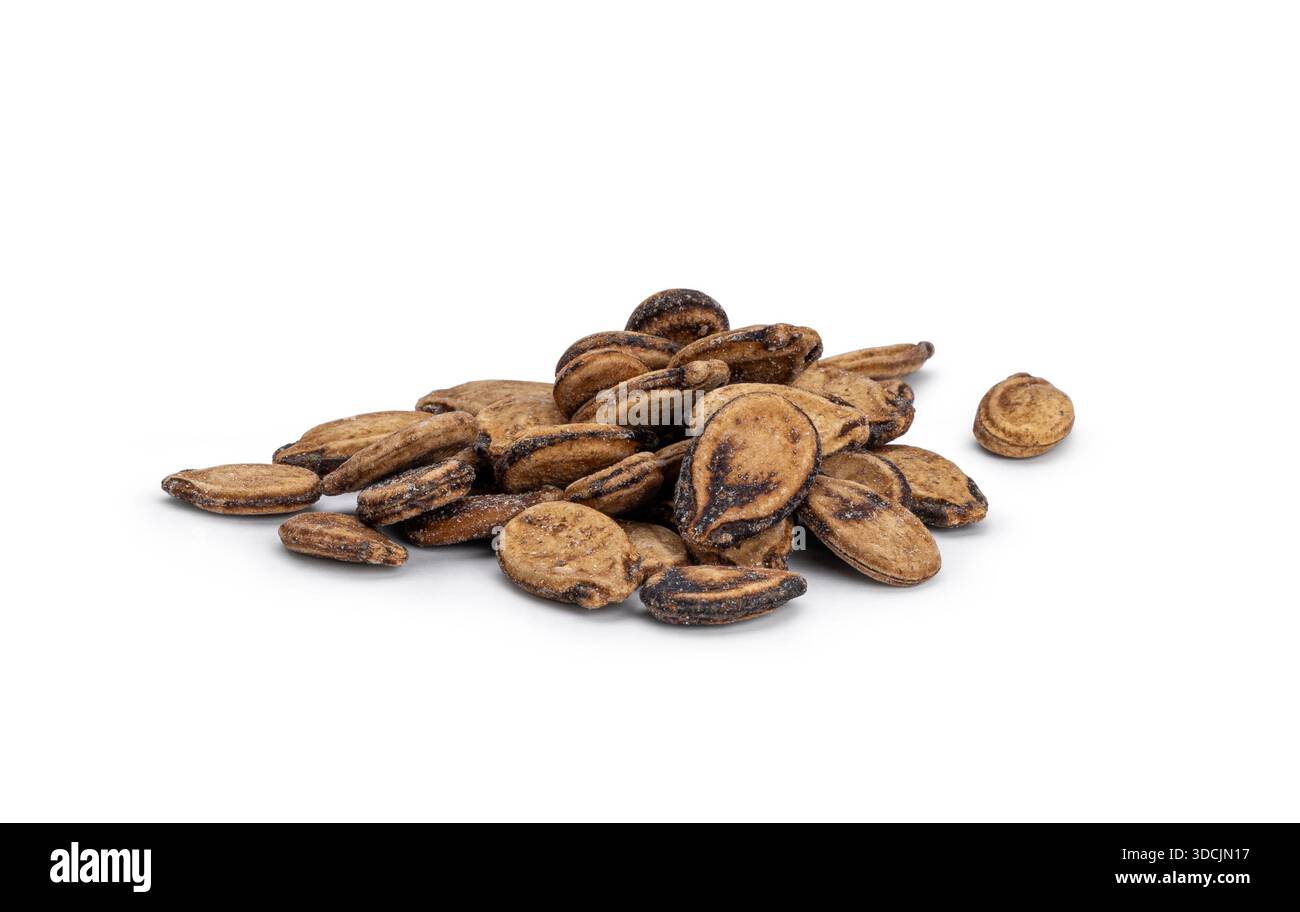 Dried watermelon seeds forming a small pile on a solid white surface Stock Photo