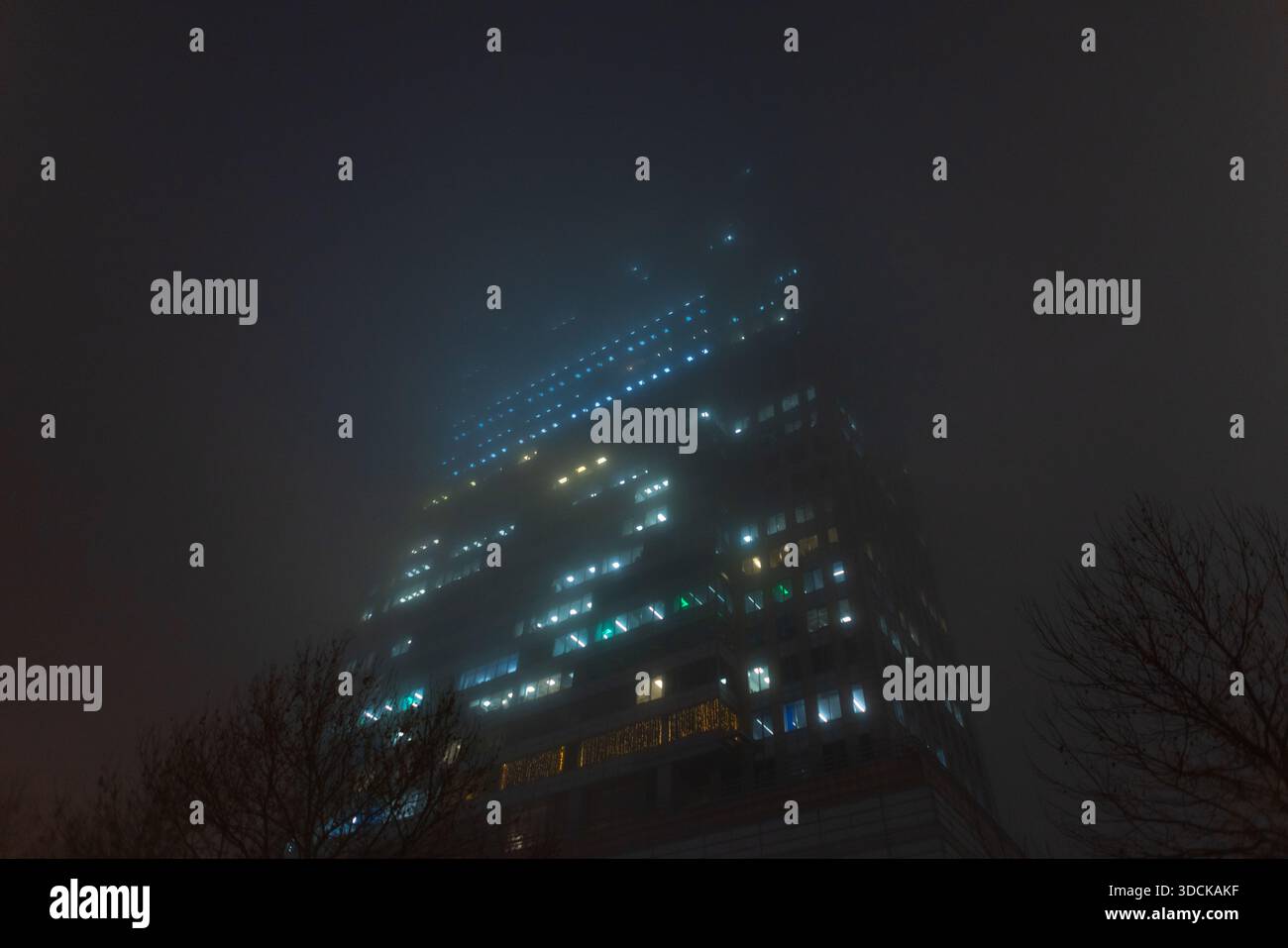 high-rise building illuminated at night, showcasing urban energy consumption and electricity usage in a modern city. The soft diffusion of electric li Stock Photo