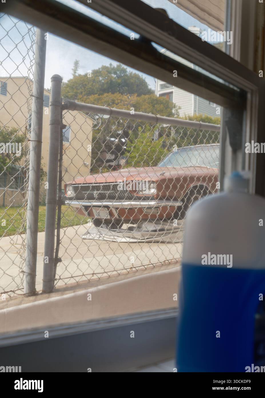 Vintage car parked behind chain link fence seen through kitchen window, Santa Monica, California, USA Stock Photo